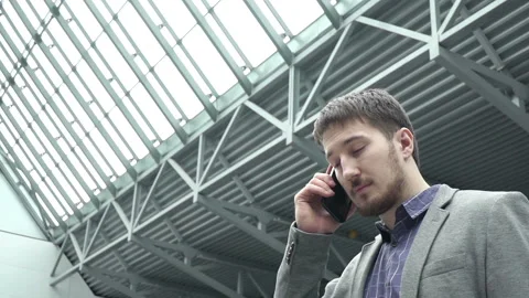 One man in jacket goes and answers the call and hear other party. Human walks in 스톡 동영상 199487497