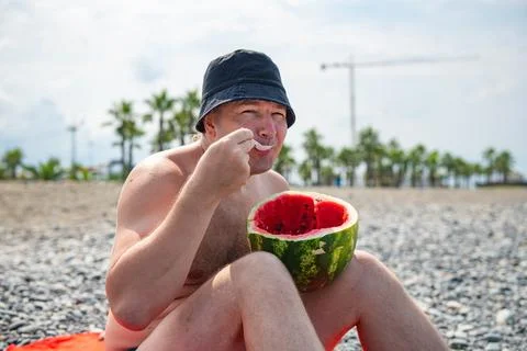 One man in panama eats watermelon on the beach Stock Photos