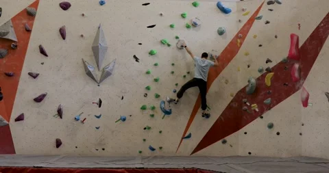 One man practices on a climbing wall, bouldering, long shot from back Stock Footage 194526894