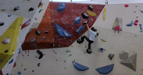 One man practices on a climbing wall, bouldering, long shot from back Stock Footage 194526916