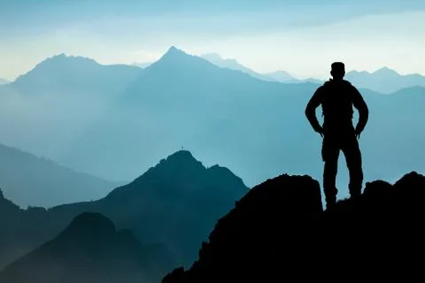 One Man reaching summit after climbing and hiking enjoying freedom and looking Stock Photos