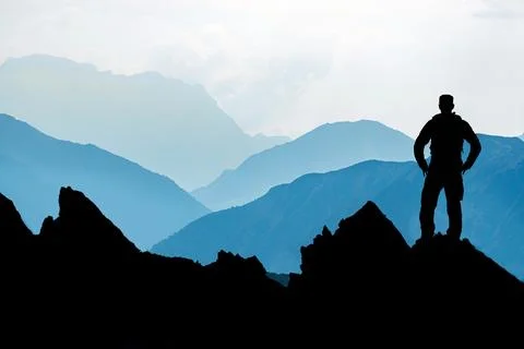 One Man reaching summit after climbing and hiking enjoying freedom and looking Stock Photos