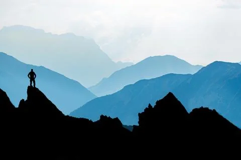 One Man reaching summit after climbing and hiking enjoying freedom and looking Stock Photos