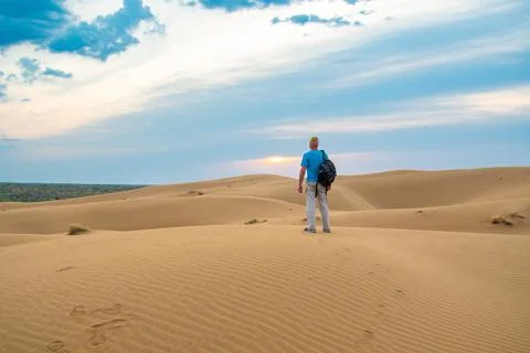 One man stands on a sand dune in the Kyzylkum desert at sunrise. Stock Photos