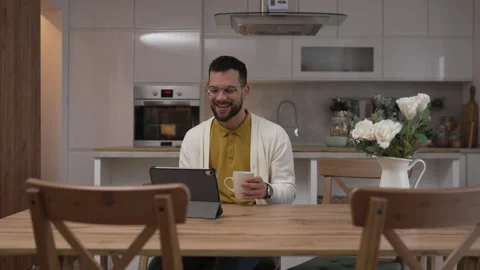 One man use digital tablet have video call online and hold cup at home Stock Footage 276477557