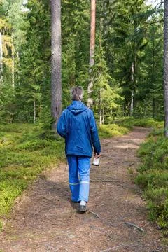One man walking along a path in a green forest. Stock Photos