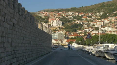 One man walking along a stone wall on the seafront in Dubrovnik, Croatia Stock Footage 60414479