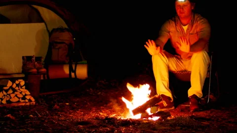 One man warms himself by the campfire outdoors. Stock Footage 92613173