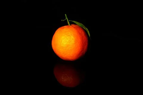 One mandarin with one leaf  isolated on black with reflection Stock-Fotos