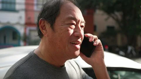 One middle aged Asian man speaking on phone in street. Happy person listening Stock Photos