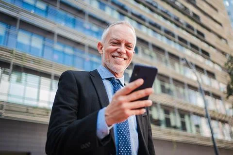 One middle aged businessman using a cellphone to watch his finances outside Stock Photos