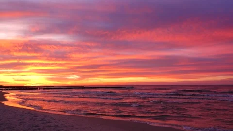 One minute 4K loop dramatic sunset over ocean beach with pink clouds and soot Stock Footage 347200042