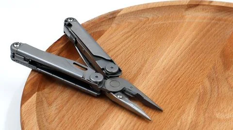 One modern open folding multifunctional knife made of gray iron on a wooden Fotos Stock