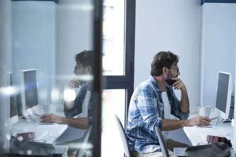 One modern worker using computer and looking screen with doubts. Office job.. Stock Photos