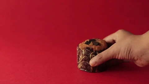One muffin or cupcake picked up by hand and placing back. shot in red backgro Stock Footage 219973444