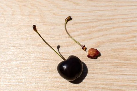 One normal red bing cherry next to one  stem of an eaten cherry fruit. Stock Photos