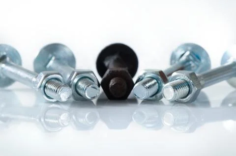 One old rusty screw among four new screws. Stock Photos