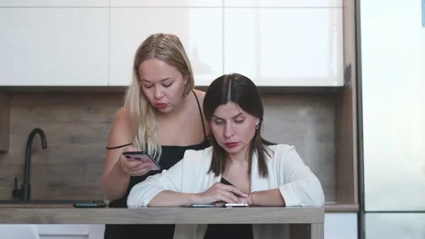 One on one meeting. Two young business women are sitting at a table at home. The Stock Footage 234215683