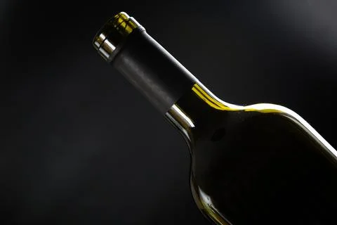 One open bottle of wine on a dark glossy background. Stock Photos