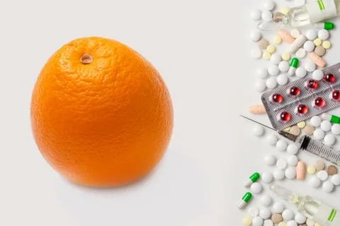One orange and heap of pills. White background. Stock Photos
