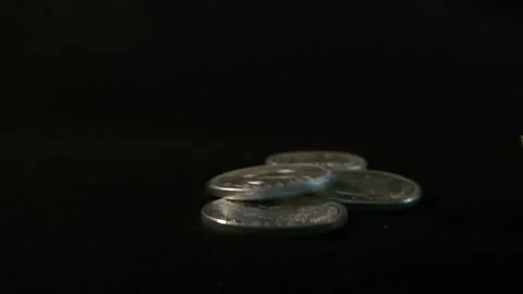 One ounce silver coins roll across the screen some coming to a halt in a pile Stock Footage 245370070