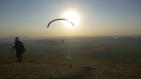 One paraglider flies in front of the mountain, the second prepares to take off Video stock 83706006