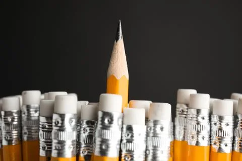 One pencil with sharp point standing out from others on black background, clo Stockfoto's