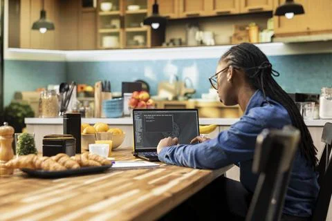 One person coding on laptop in a kitchen representing remote work 写真素材
