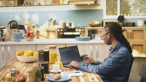 One person coding on laptop in kitchen representing remote work Stock Photos
