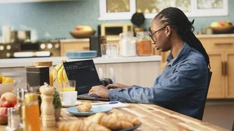 One person coding on laptop in kitchen representing remote work Stock Photos