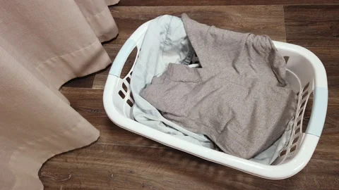 One person throws clothes to be ironed into a plastic tub Stock Footage 220734698