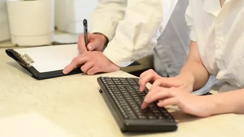 One person typing on a keyboard, while another takes notes in a folder. Teamwork Stock Footage 317994713