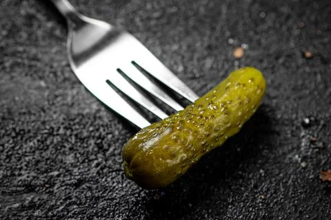 One pickled cucumber on a fork. Stock Photos