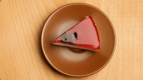 One piece of chocolate cake lying on a plate spins around its axis. Stock Footage 107730679