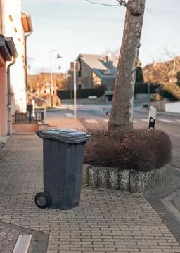 One plastic garbage container standing on a city street. Stock Photos