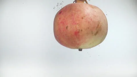 One pomegranate fall into the water with splashes and bubbles in slow motion. Видео 144487251