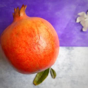 One Pomegranate with its leaf placed beautifully in white and violet paper ba Stock Photos