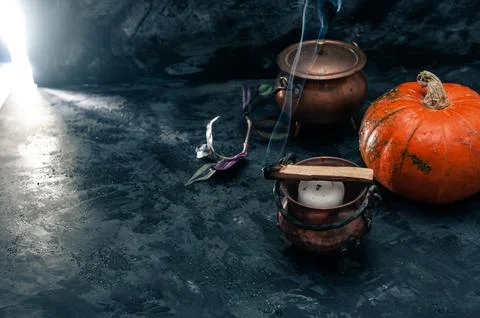 One pumpkin squash and copper or brass witch pots with candles and palo santo Stock Photos