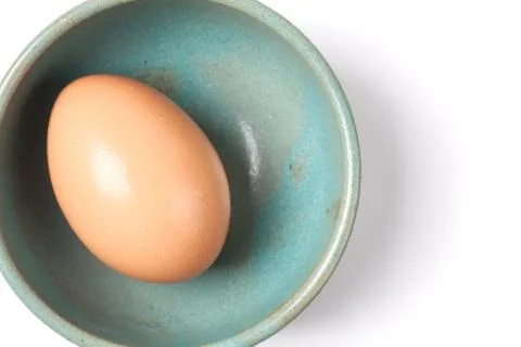 One raw egg on green plate on white from top view with space for copy. Stock Photos