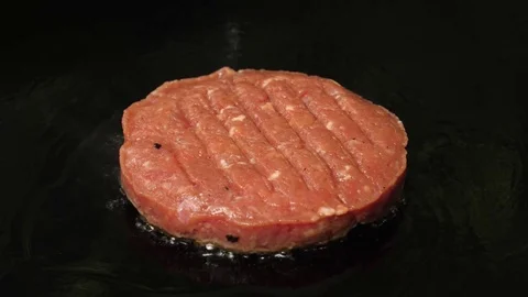 One raw minced beef patty grilling on the frying surface with oil, 4K 60 FPS 動画素材 76897483