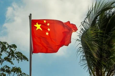 One rectangular red colored flag with yellow stars is on a blue sky backgroun Stock Photos