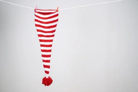 One red and white striped cap hanging from a rope on a white background. Foto stock
