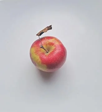 One red apple with dried leaf placed on textured white background. Stock Photos