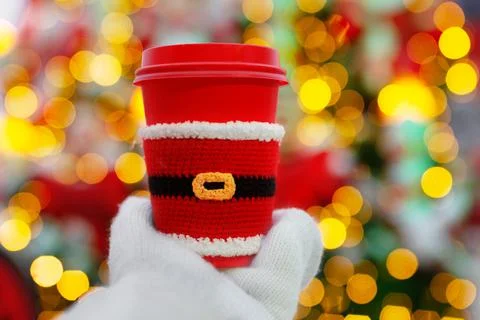 One red beige cups with white lid dressed in santa claus clothes in palm of hand Stock Photos