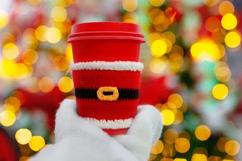 One red beige cups with white lid dressed in santa claus clothes in palm of h Stock Photos