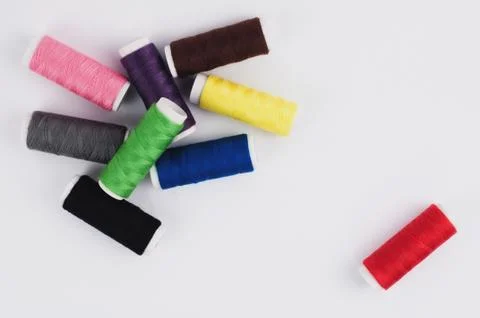 One red bobbin of thread near heap of bobbins of new colorful threads Foto stock