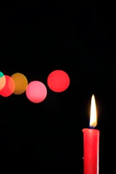 One red candle on the background of colored balls Stock Photos