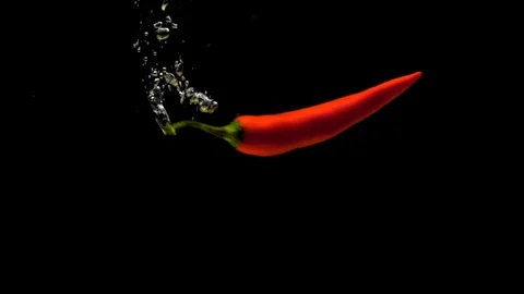 One red chili falling into transparent water on black background Stock Footage 118127770