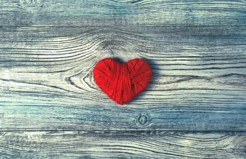 One red heart made of thread on a wooden textured gray-blue background. Stock Photos
