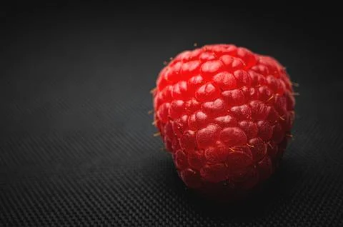 One red raspberry on a black background macro shot Stock Photos